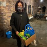volunteer michelle on POWER House porch with box of gifts