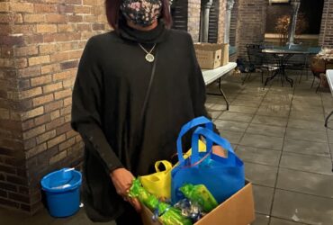 volunteer michelle on POWER House porch with box of gifts